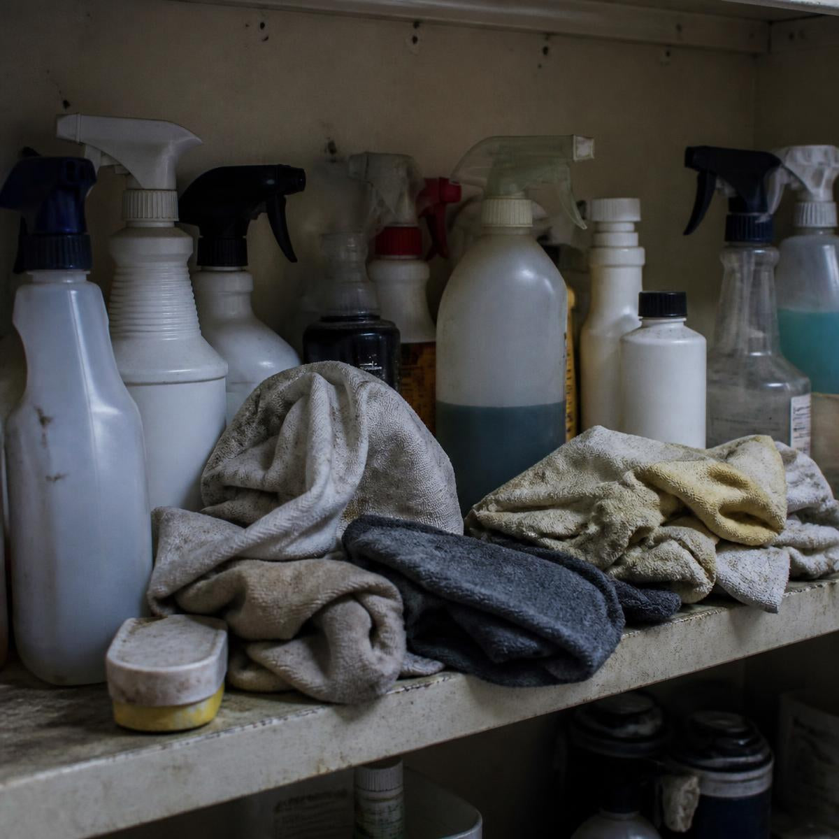 A cluttered shelf of half-used spray cleaners